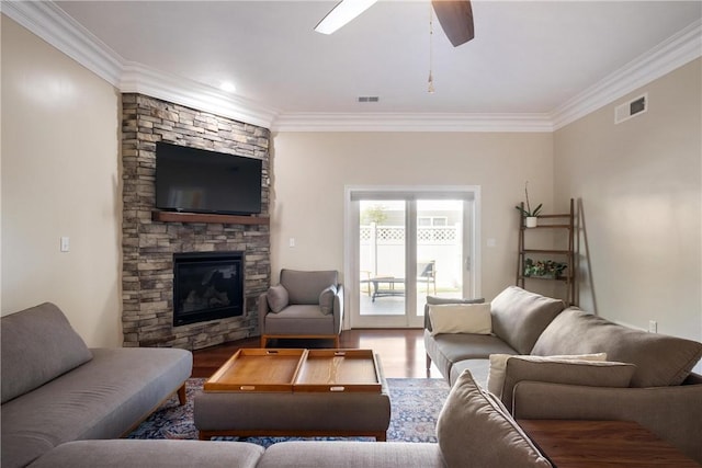 living room with hardwood / wood-style floors, crown molding, and a stone fireplace