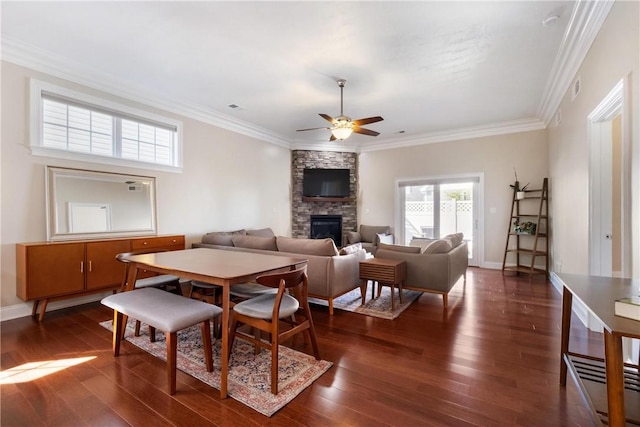 living room with crown molding, dark wood-type flooring, a fireplace, and ceiling fan