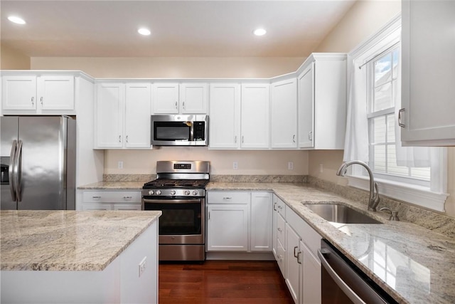 kitchen with appliances with stainless steel finishes, sink, white cabinets, and light stone counters