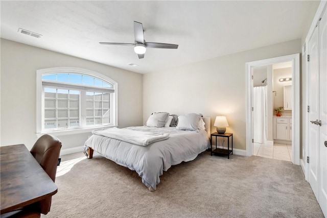 bedroom featuring light carpet, ensuite bath, and ceiling fan