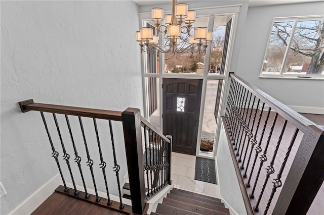 stairs with hardwood / wood-style floors and a notable chandelier