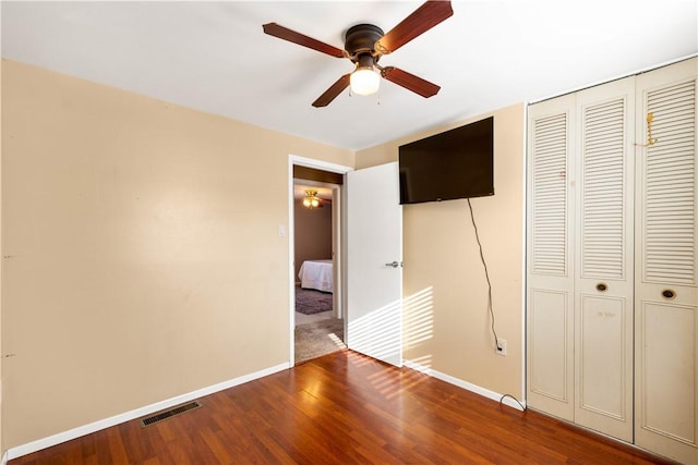 unfurnished bedroom featuring hardwood / wood-style flooring, a closet, and ceiling fan