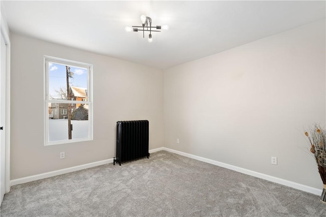 spare room with radiator heating unit and light colored carpet