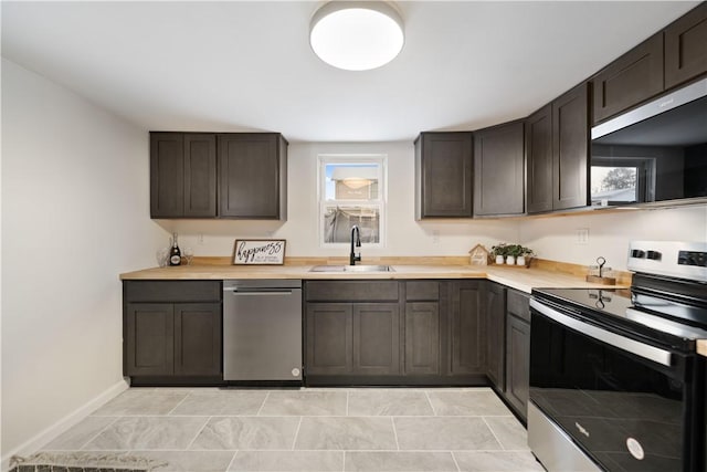 kitchen with dark brown cabinetry, sink, light tile patterned floors, and stainless steel appliances