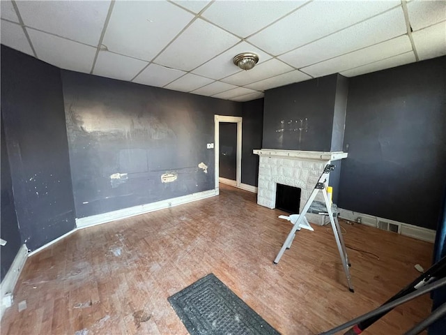 unfurnished living room featuring hardwood / wood-style floors, a fireplace, and a paneled ceiling