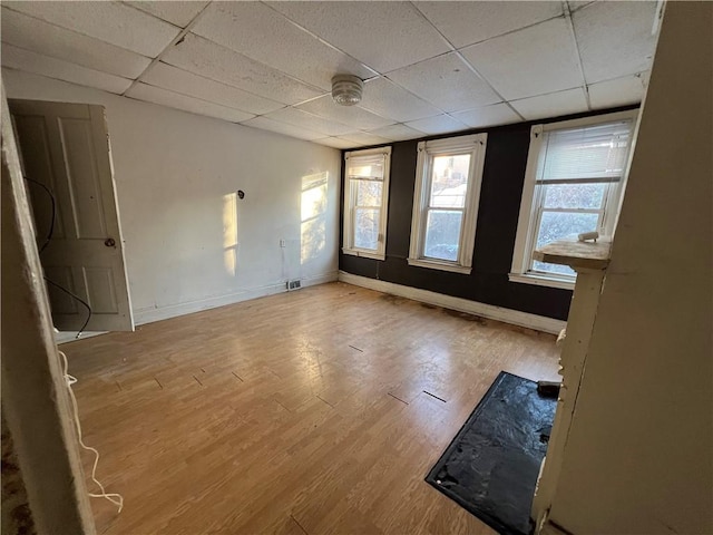 spare room with a drop ceiling and light hardwood / wood-style flooring