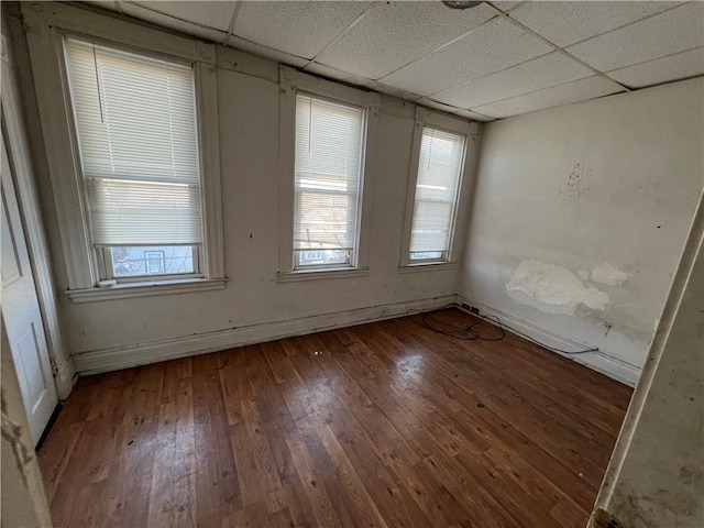 unfurnished room with a paneled ceiling and dark hardwood / wood-style flooring