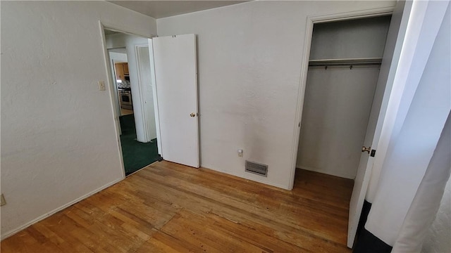 unfurnished bedroom featuring hardwood / wood-style floors and a closet