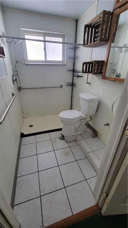 bathroom featuring a wealth of natural light, tile patterned floors, toilet, and a shower