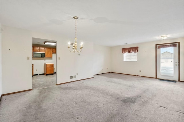 carpeted empty room featuring a chandelier