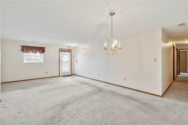 carpeted spare room with a notable chandelier