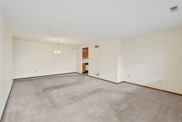 carpeted spare room featuring an inviting chandelier