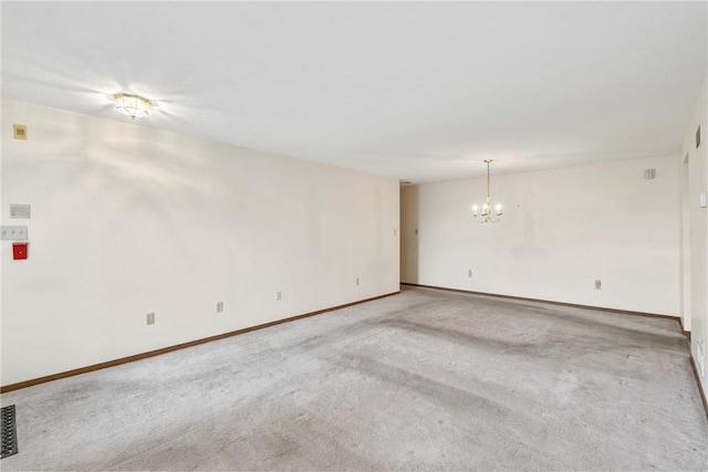 spare room featuring an inviting chandelier and carpet