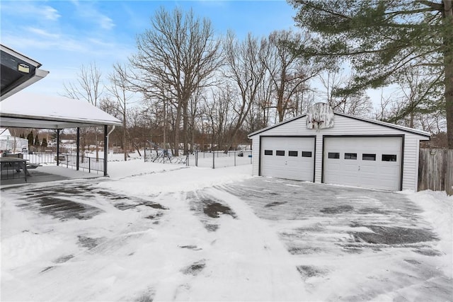 yard layered in snow featuring an outbuilding and a garage