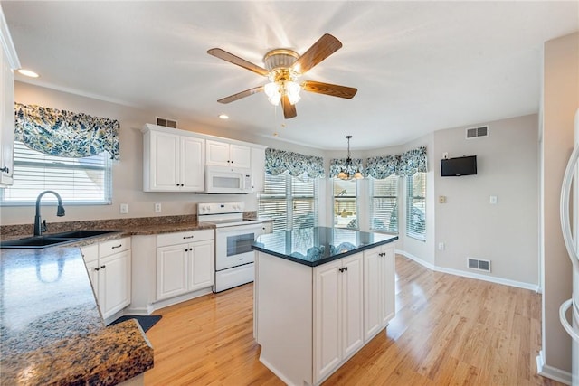 kitchen featuring sink, light wood-type flooring, a kitchen island, white appliances, and white cabinets