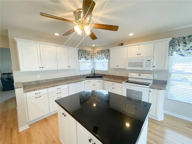 kitchen with white cabinetry, sink, light wood-type flooring, a center island, and white appliances