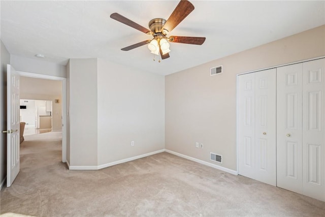 unfurnished bedroom featuring light colored carpet, ceiling fan, and a closet