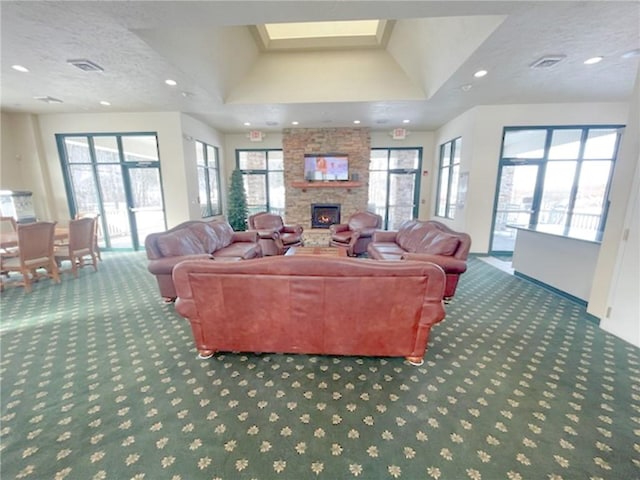 living room featuring a stone fireplace, dark carpet, and a textured ceiling