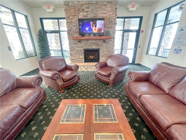 carpeted living room with a stone fireplace