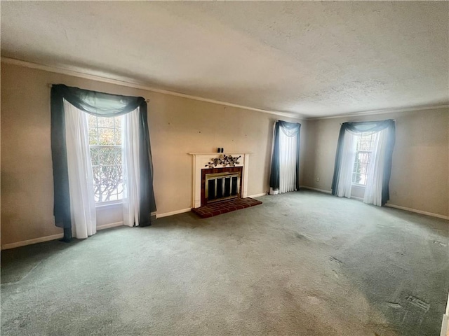 unfurnished living room with a tiled fireplace, a wealth of natural light, a textured ceiling, and carpet flooring