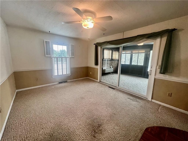 unfurnished room with ceiling fan, carpet floors, and a textured ceiling