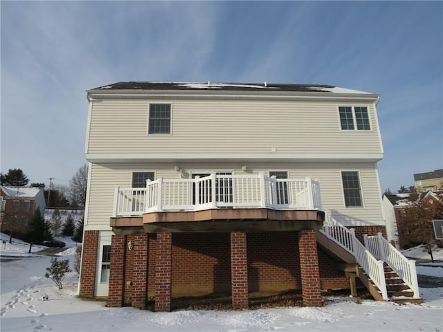 snow covered rear of property with a wooden deck