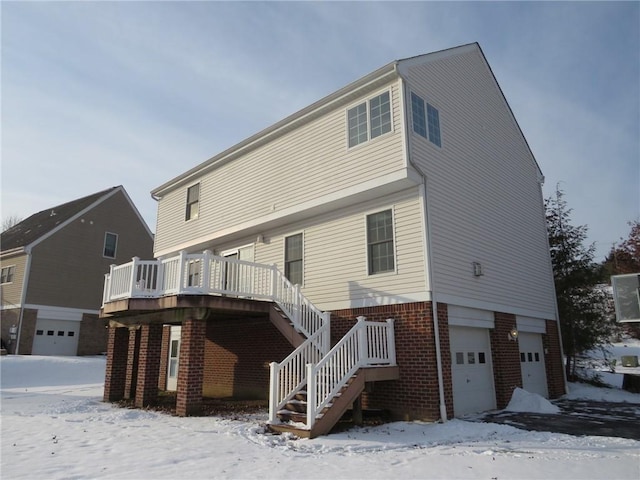 snow covered house with a wooden deck and a garage