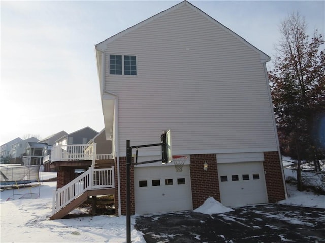 view of snowy exterior with a garage and a trampoline