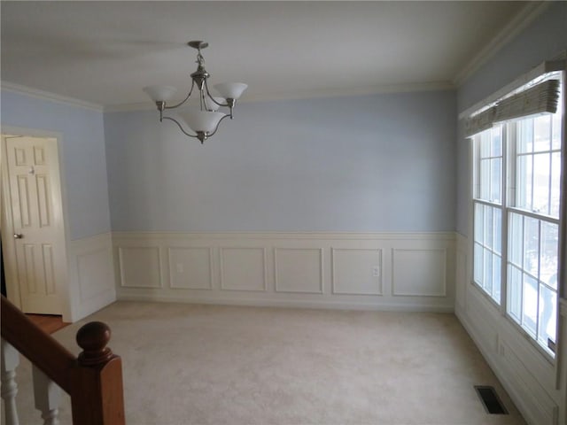 carpeted spare room with ornamental molding and an inviting chandelier