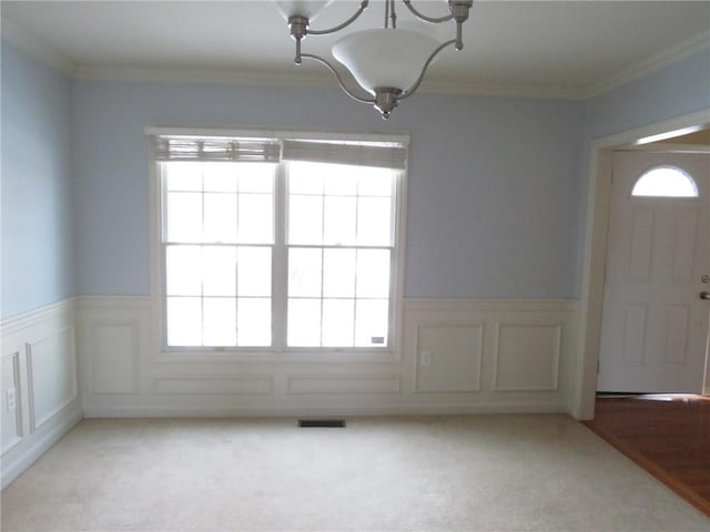 unfurnished dining area with light carpet, a notable chandelier, and ornamental molding