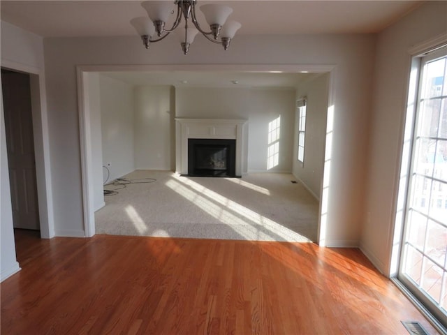 unfurnished living room featuring a chandelier and light carpet