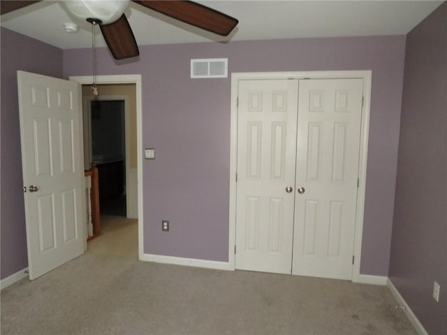 unfurnished bedroom featuring ceiling fan, light colored carpet, and a closet