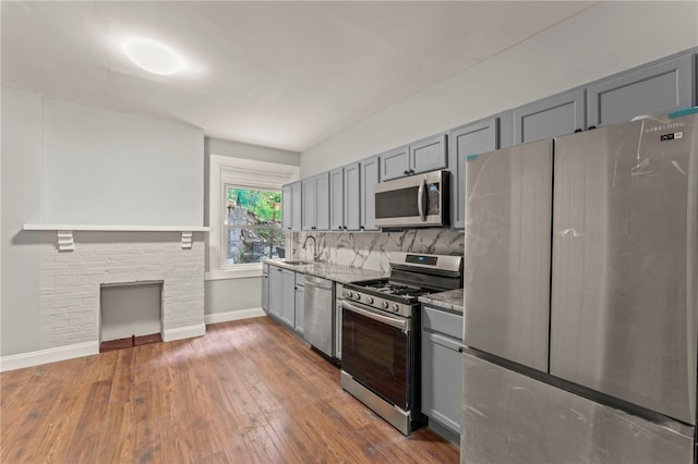 kitchen featuring dark wood-type flooring, sink, gray cabinets, stainless steel appliances, and decorative backsplash