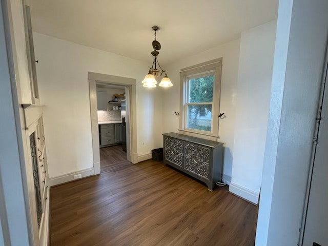 unfurnished dining area featuring an inviting chandelier and dark hardwood / wood-style flooring