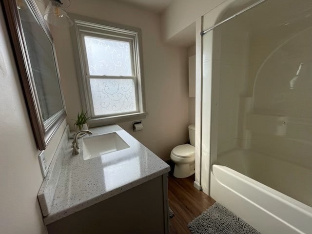 full bathroom with hardwood / wood-style flooring, vanity, bathing tub / shower combination, and toilet