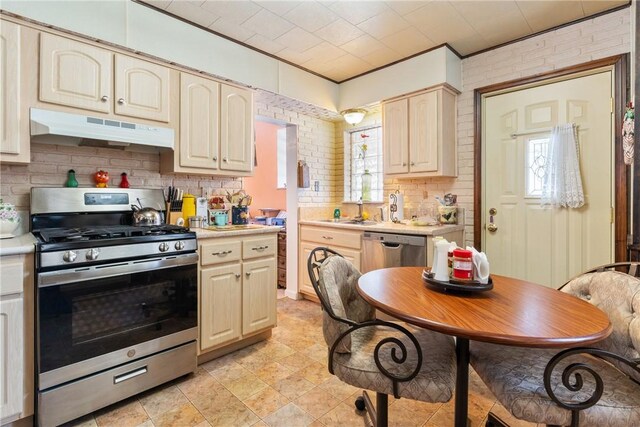 kitchen featuring brick wall, appliances with stainless steel finishes, sink, decorative backsplash, and ornamental molding