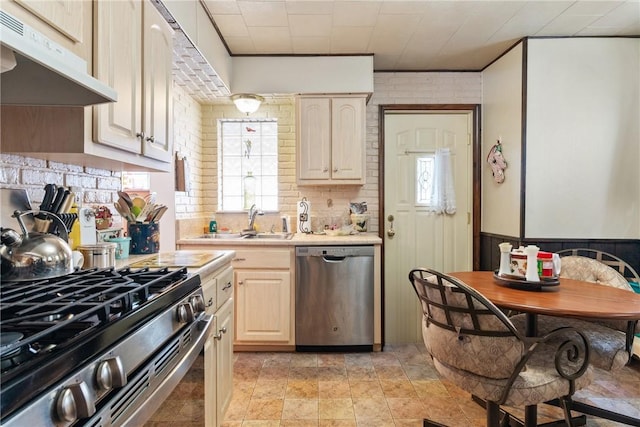 kitchen with brick wall, appliances with stainless steel finishes, and sink