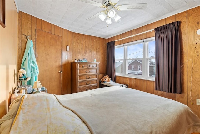 bedroom with ceiling fan and wooden walls