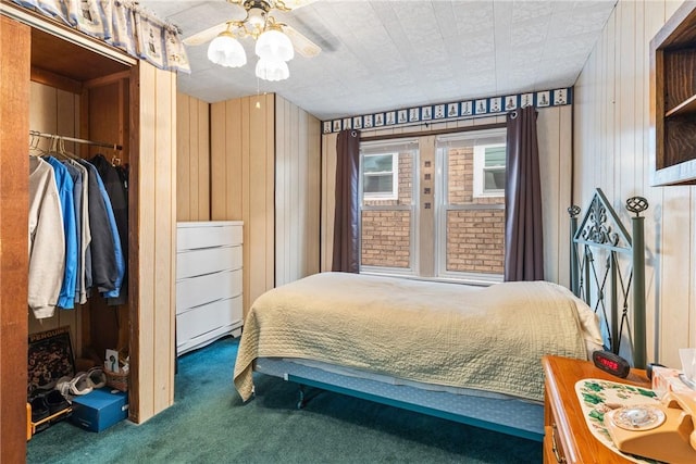 carpeted bedroom with a closet, ceiling fan, and wood walls