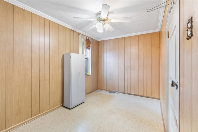 empty room with crown molding, ceiling fan, and wood walls