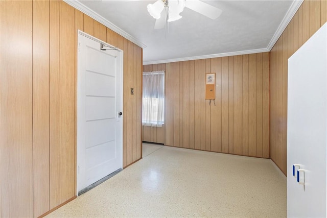 spare room featuring wooden walls, ornamental molding, and ceiling fan