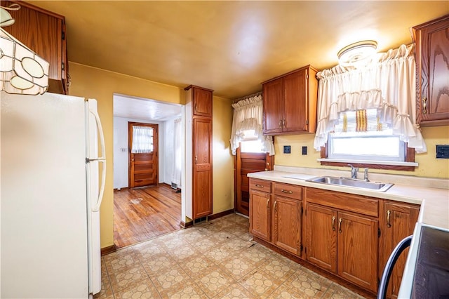 kitchen with stove, sink, a healthy amount of sunlight, and white fridge