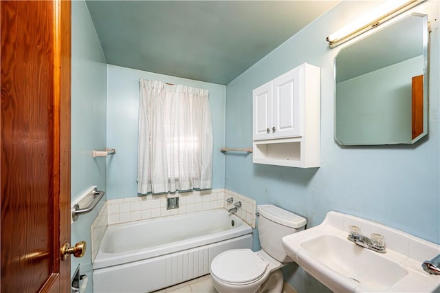 bathroom with sink, tile patterned floors, toilet, and a tub to relax in