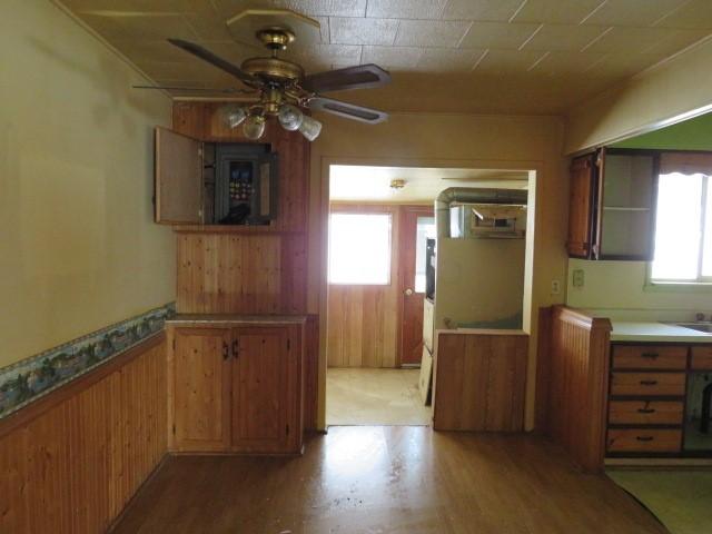 kitchen featuring ceiling fan, wooden walls, and wood-type flooring