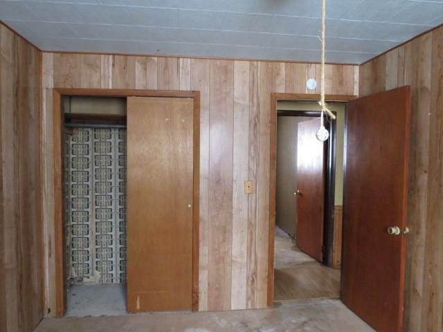 unfurnished bedroom featuring wooden walls and a closet