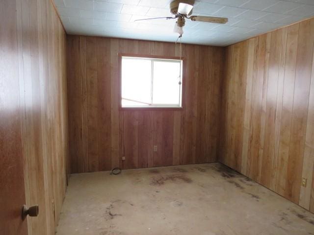 empty room with ceiling fan and wood walls