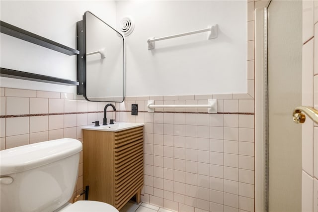 bathroom with vanity, toilet, and tile walls