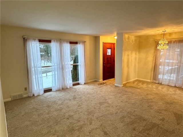 carpeted spare room featuring a chandelier