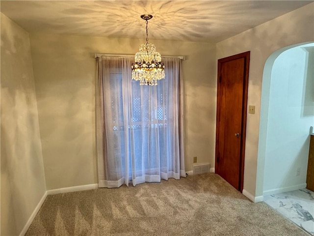 carpeted spare room featuring a chandelier