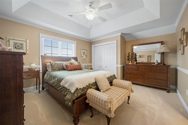 carpeted bedroom with a closet, ornamental molding, ceiling fan, and a tray ceiling